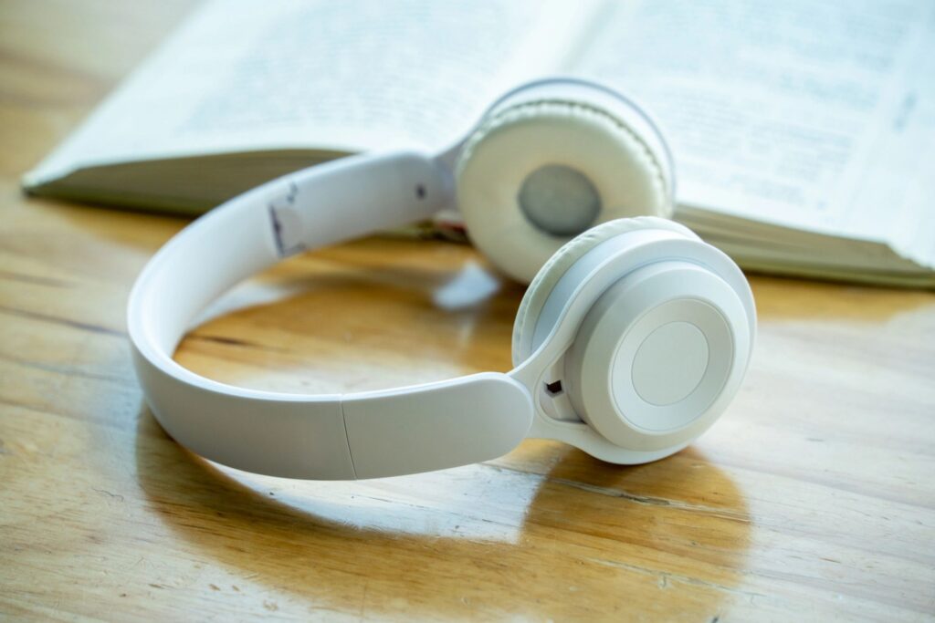 White Headphones Resting on Wooden Table Near Open Book
